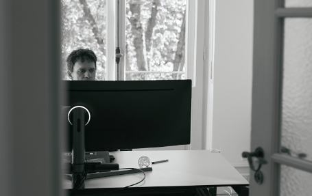 Mitarbeiter sitzt am Schreibtisch hinter dem Monitor