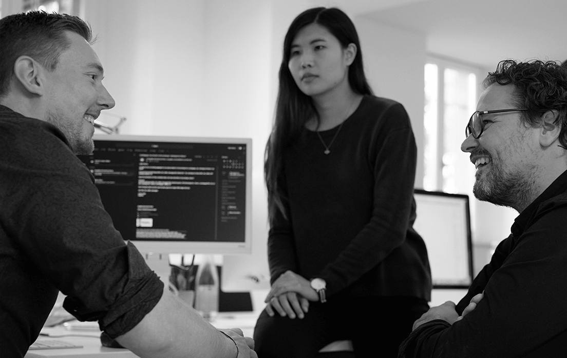 Gespräch unter drei Kollegen am Schreibtisch