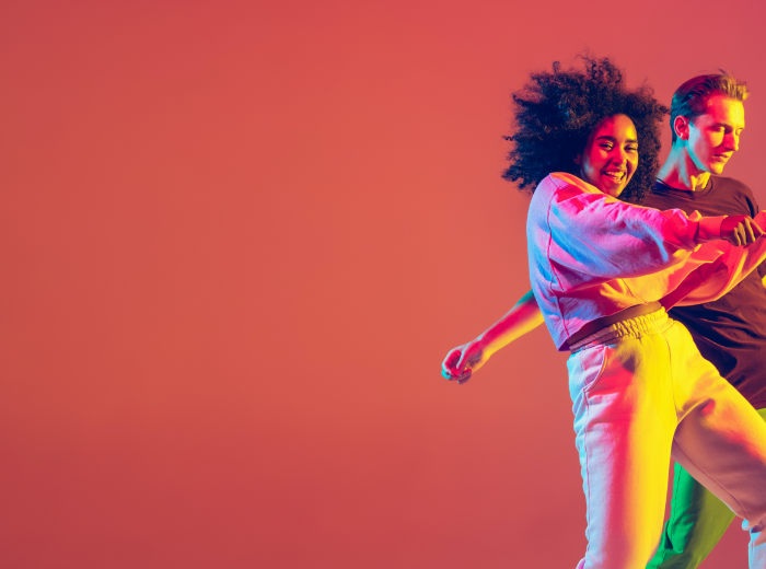 Zwei tanzende Personen an der rechten Seite, die bunt beleuchtet sind